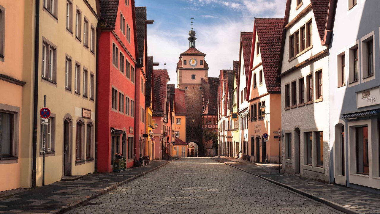 A cobbled street running to a clock tower gate.