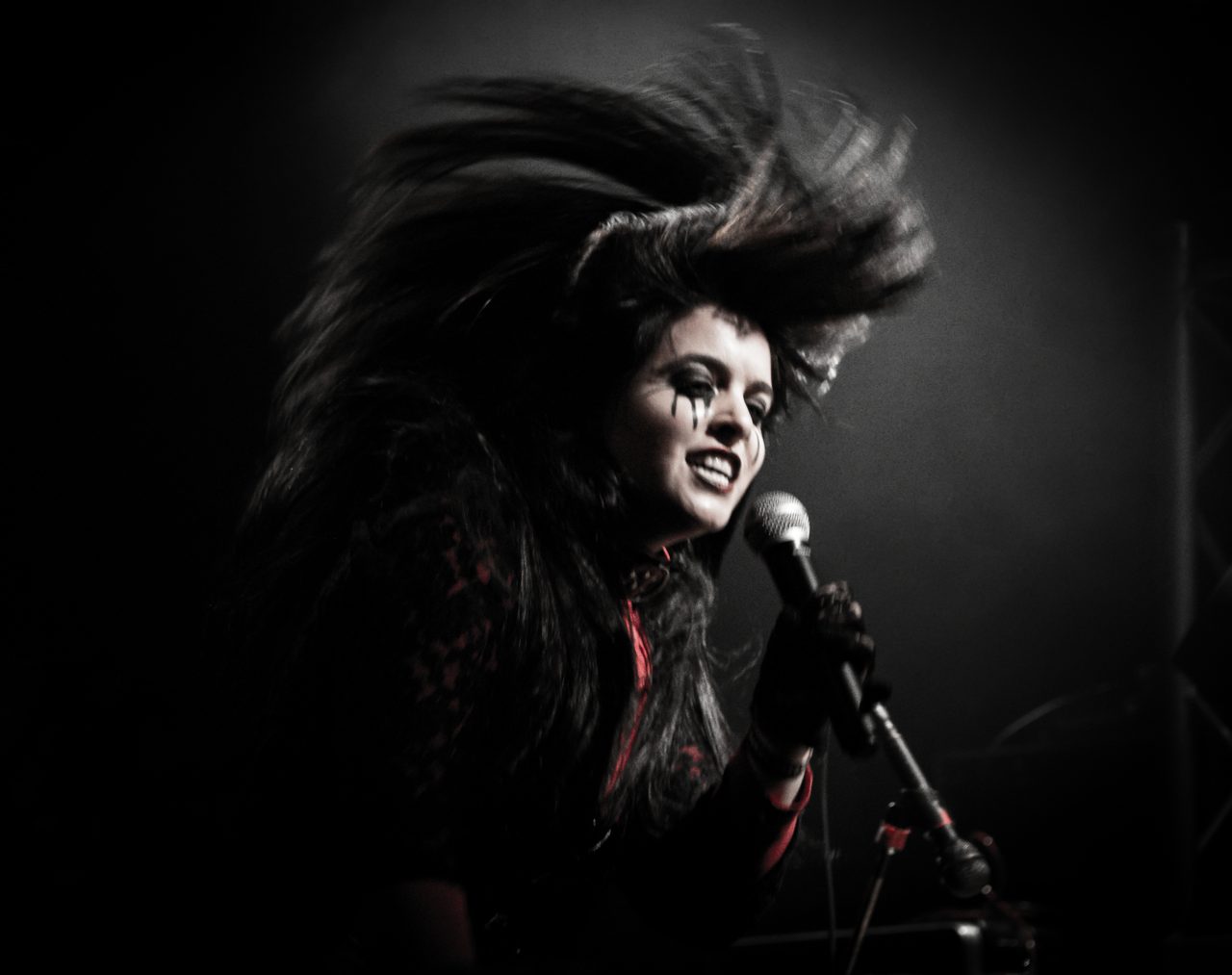 Sharone mid hair flip, black tears painted down her cheek.