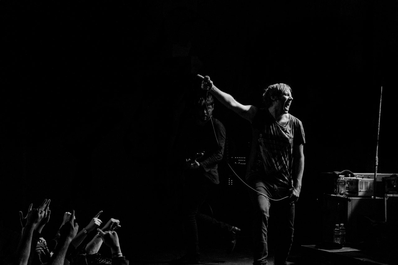 Thursday over the crowd, one arm pointing across the dark.