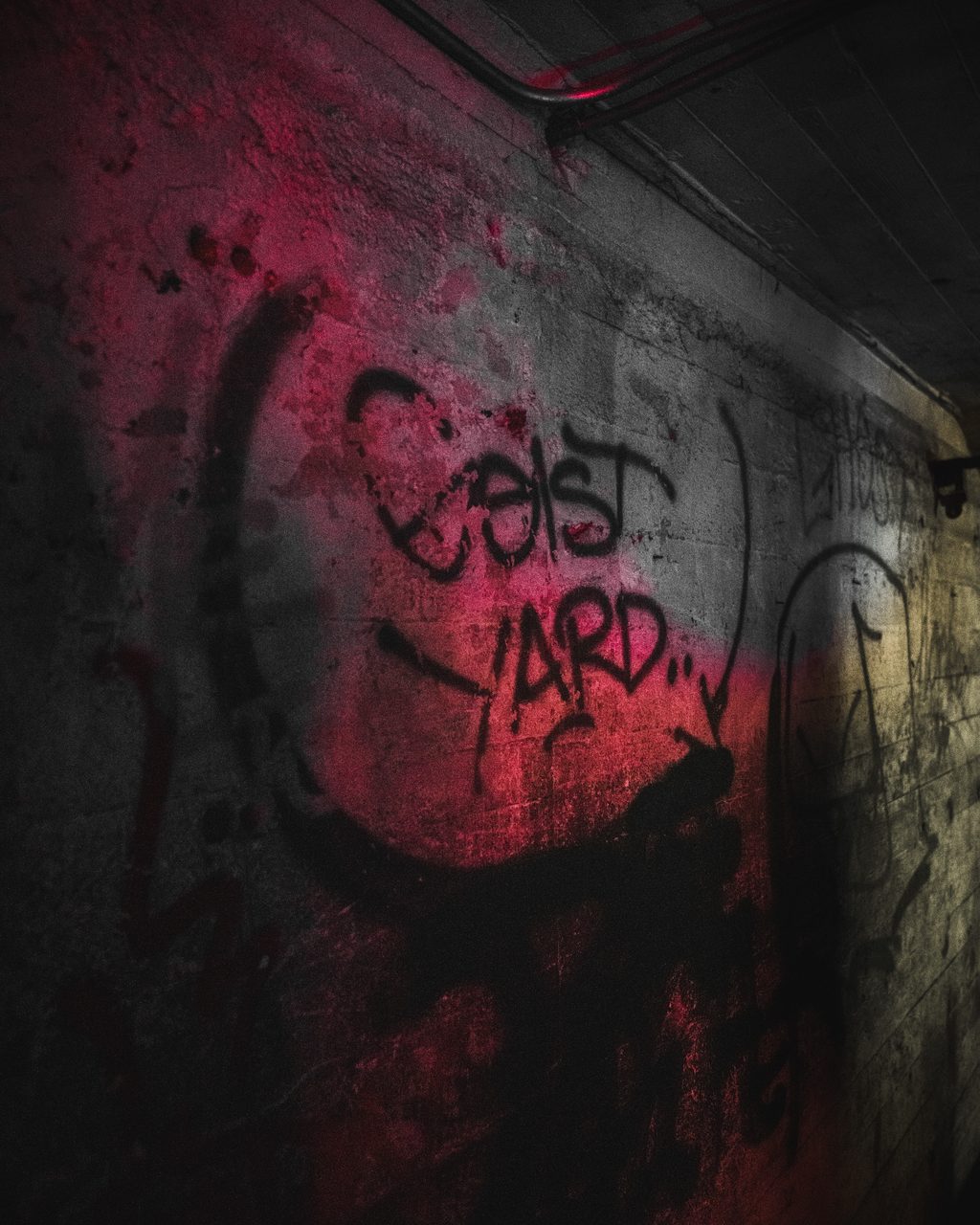 Spray paint on a concrete wall, lit red down one side and grey down the other.