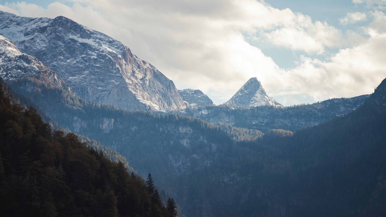 A snow peak between forested ridges.