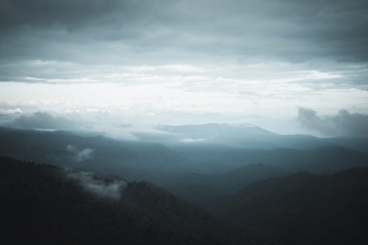 Blue ridgelines under low cloud, mist rising out of the valleys.